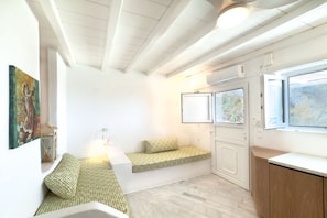 Quarto com um banco embutido, uma cama, uma janela com vista e um quadro na parede.