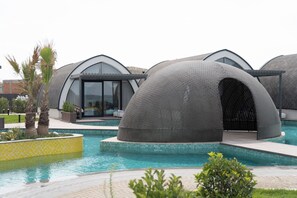 Un hotel modern amb estructures en forma de cúpula, piscina i jardí ben cuidat.