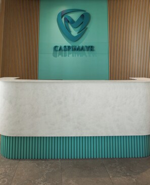A reception desk with a logo and the name "CASPIMAYR" on the wall behind it. - Caspimayr Retreat Beach Resort (Baku)