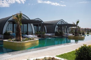 Zona de piscina amb piscina, gandules i zones d'seients cobertes.