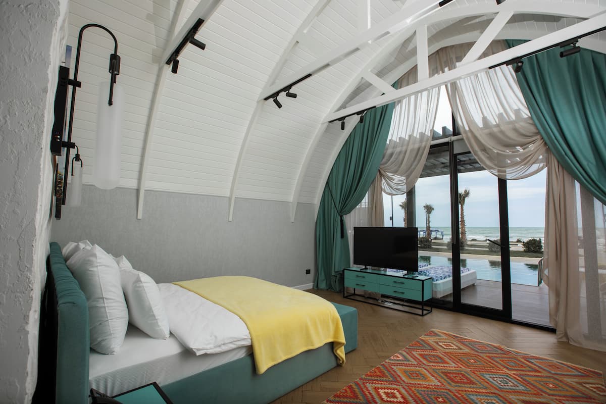 Une chambre avec un lit, une télévision et vue sur la plage.