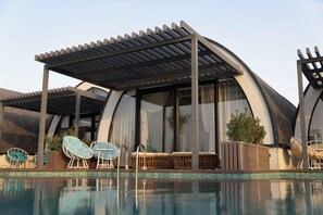 Zona de piscina amb gandules, un espai de seients cobert i una piscina.