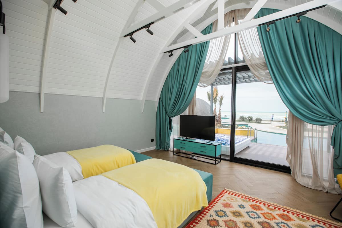 Une chambre avec deux lits, une télévision et une vue sur la piscine et la plage.