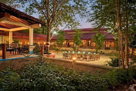 A traditional building with a tiled roof, surrounded by lush greenery and outdoor seating areas.