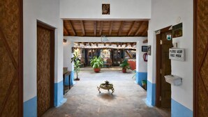 Un couloir avec un plafond en bois, des plantes en pot et un panneau indiquant que le port du masque est obligatoire.