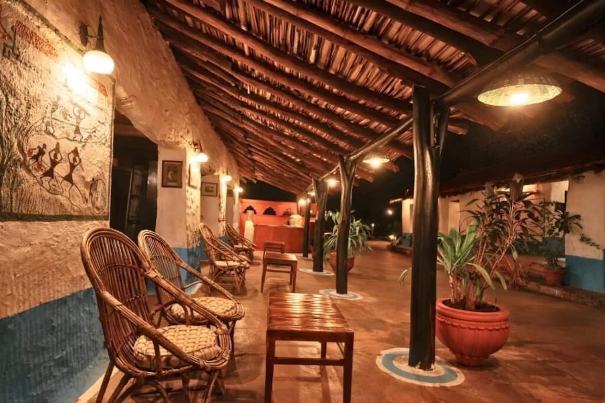 A covered outdoor area with wicker furniture, a reception desk, and potted plants.