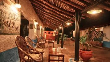 A covered outdoor area with wicker furniture, a reception desk, and potted plants.