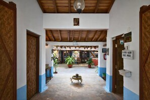 Un corridoio con soffitto in legno, piante in vaso e un cartello che richiede l'uso delle mascherine.