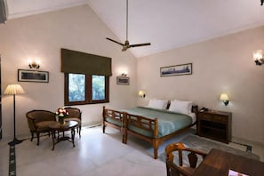 A bedroom with a bed, a chair, a table, a standing lamp, and a ceiling fan. - Justa The Bagh, Kanha (Baihar)