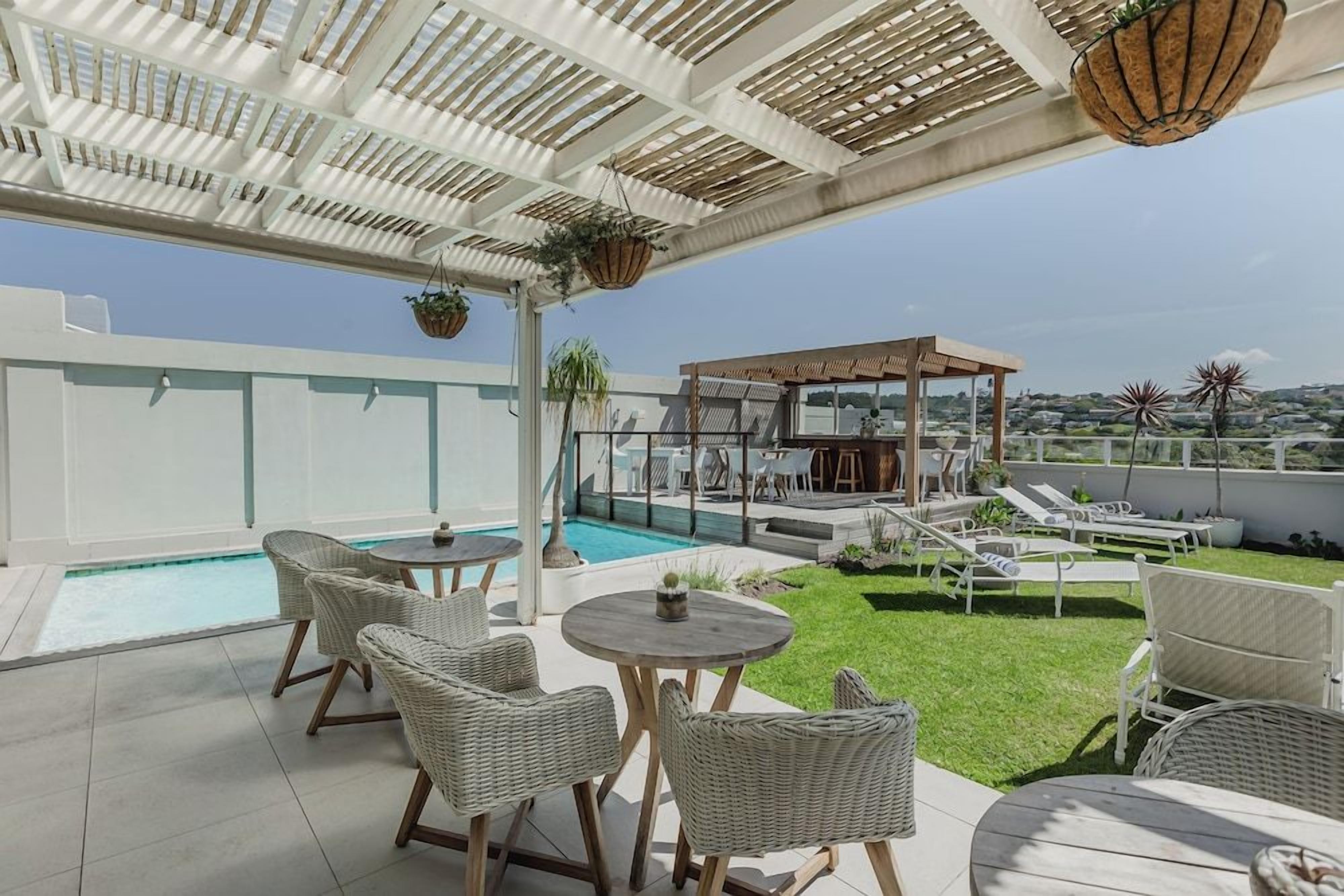 Eine Dachterrasse mit Pool, Sitzgelegenheiten im Freien und einer Pergola.