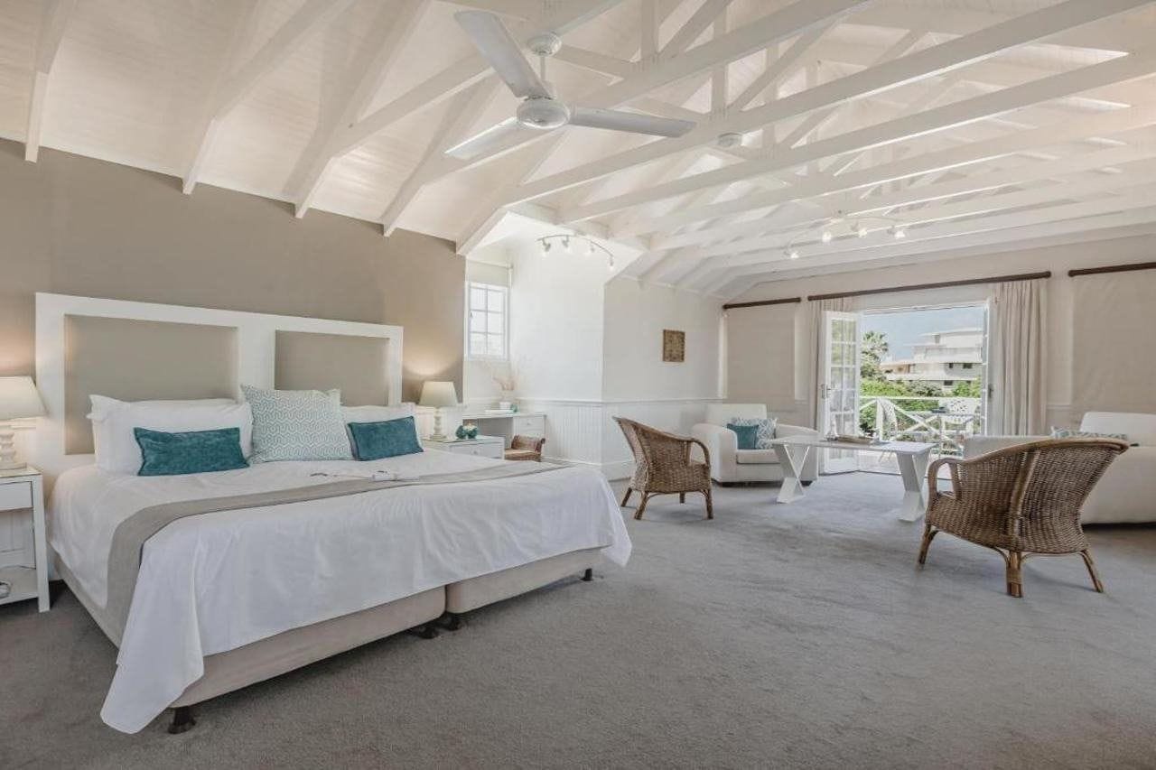 A spacious bedroom with a large bed, a ceiling fan, and a view of the outdoors.