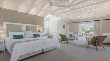 A spacious bedroom with a large bed, a ceiling fan, and a view of the outdoors.