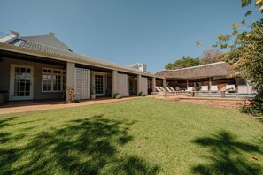 A house with a covered patio, a swimming pool, and a well-maintained lawn. - Cottage Pie Guest House (Plettenberg Bay)