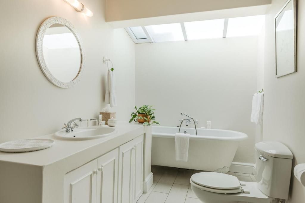 Un baño moderno con una bañera independiente, un inodoro y un lavabo con espejo.