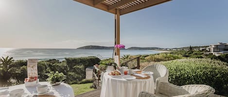 A seaside dining area with tables set for two, overlooking the ocean.