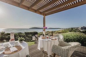 A seaside dining area with tables set for two, overlooking the ocean. - Cottage Pie Guest House (Plettenberg Bay)