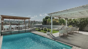 A rooftop swimming pool with a covered seating area and a view of the city.