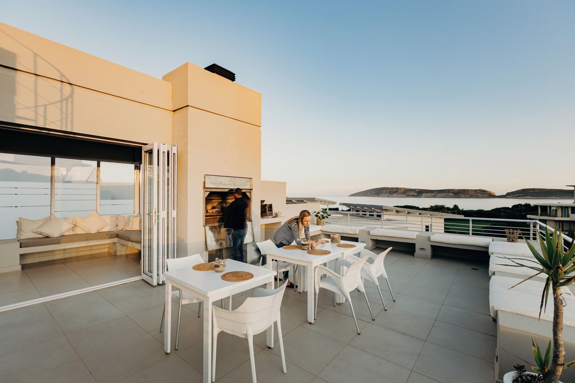 A rooftop terrace with a seating area, tables, and chairs.