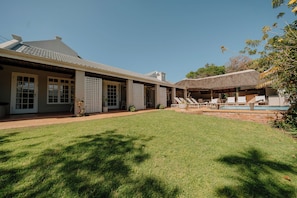 A house with a covered patio, a swimming pool, and a well-maintained lawn. - Cottage Pie Guest House (Plettenberg Bay)