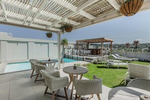 A rooftop terrace with a swimming pool, lounge chairs, and a covered seating area. - Cottage Pie Guest House (Plettenberg Bay)