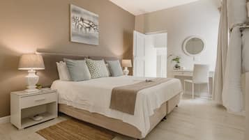 A bedroom with a bed, nightstand, desk, chair, and a mirror.
