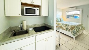 Una kitchenette compacta con microondas, pileta y alacenas.