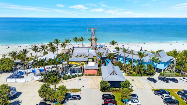 Un hotel frente al mar con vista a la playa, estacionamiento y un muelle.