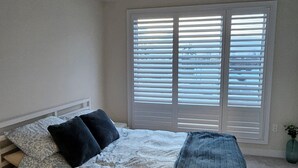 Un dormitorio con una cama, una mesita de noche y una ventana con persianas.