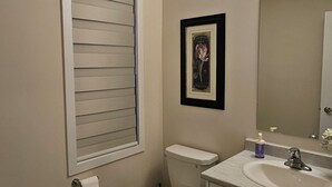 Un baño con inodoro, lavamanos y ventana con persianas.