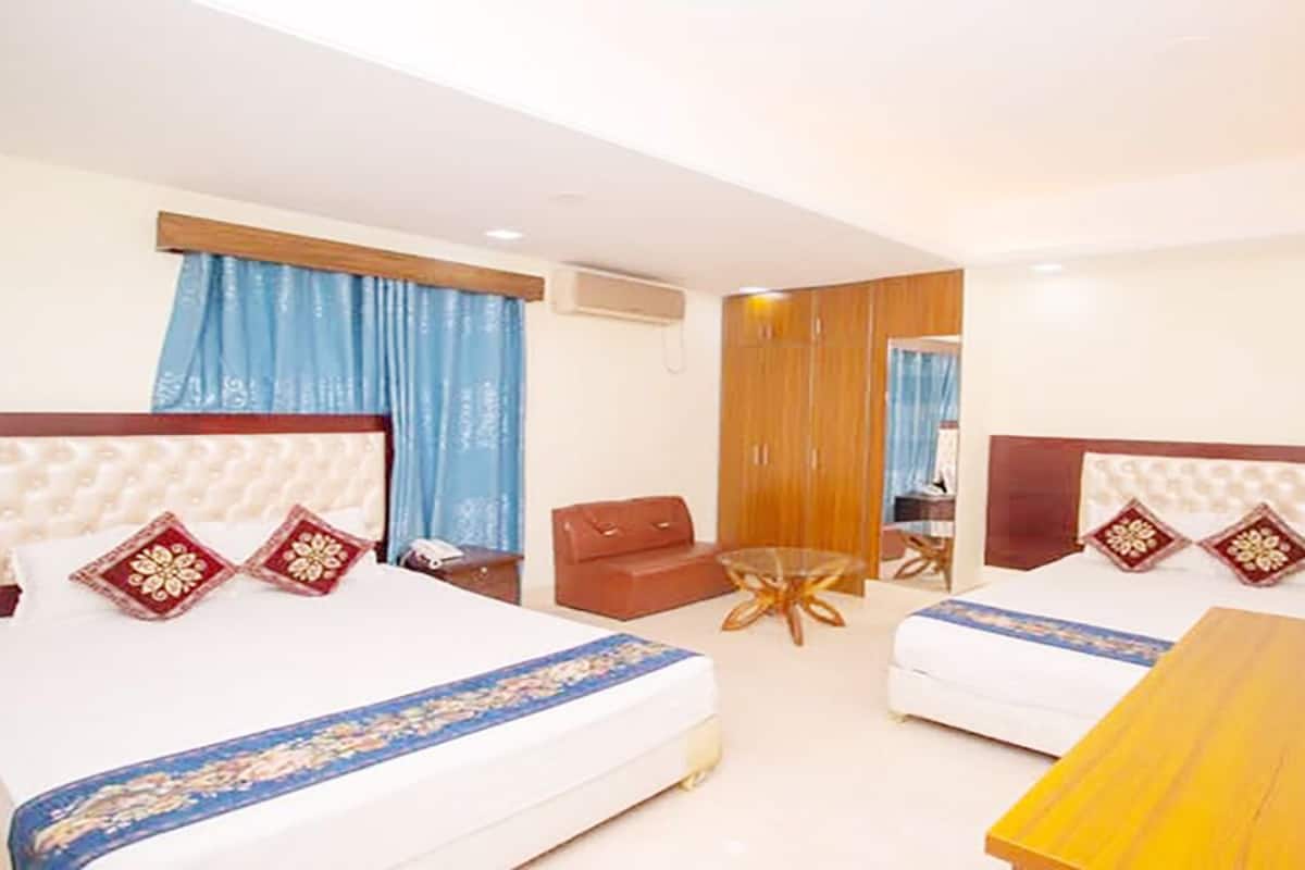 A hotel room with two beds, a wooden table, a sofa, and a TV.
