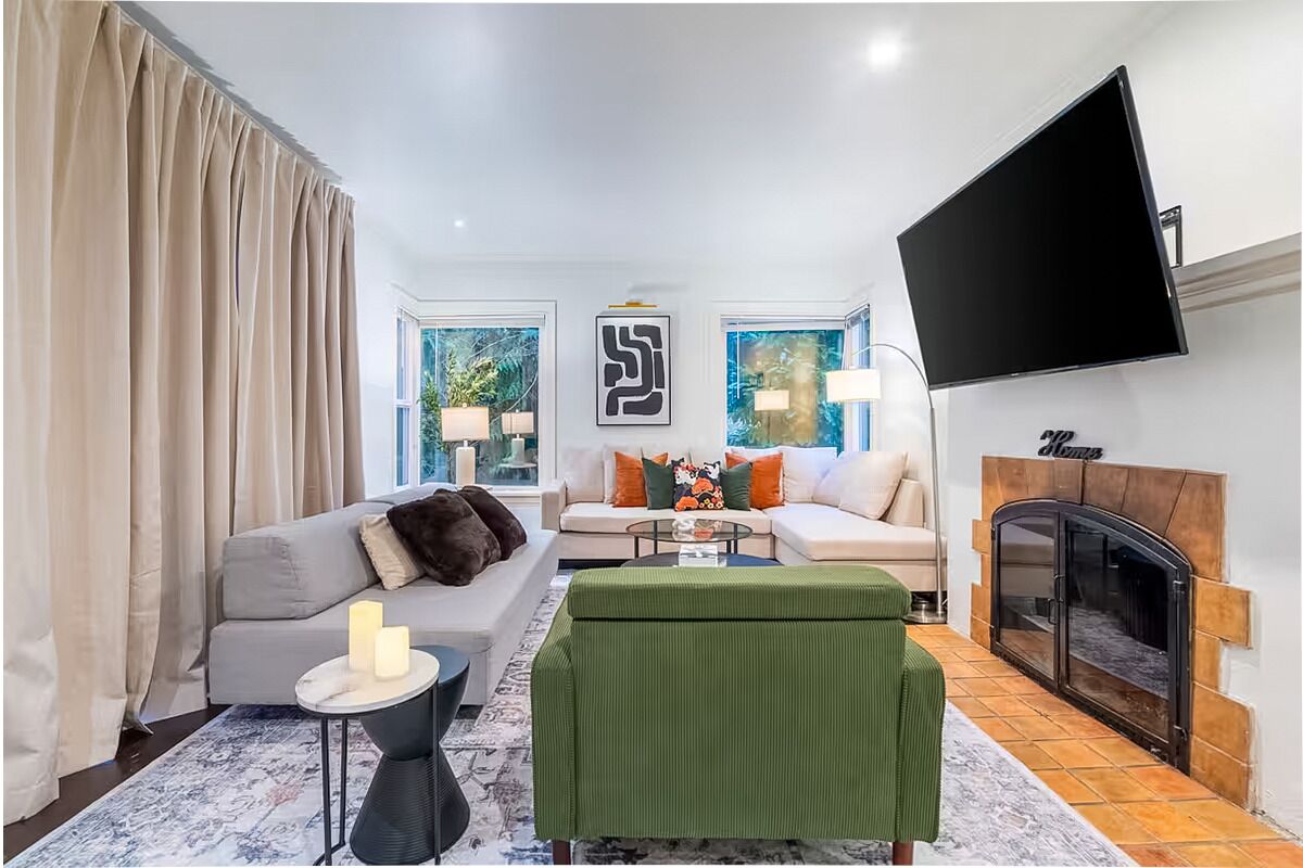 Ein modernes Wohnzimmer mit zwei Sofas, einem Couchtisch, einem an der Wand montierten Fernseher und einem Kamin.