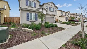 A residential neighborhood with houses featuring two-story designs, front yards with mulch and plants, and a clear sky. - Sleeps ~12, 5 Bedroom 3 Bath Home in Lincoln CA (Lincoln)