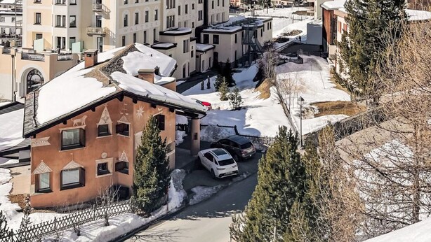 Ein Hotel mit einem markanten Turm, verschneiter Umgebung und freiem Blick auf die Berge im Hintergrund.
