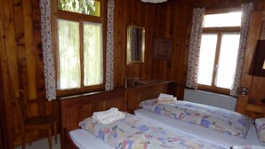A wooden room with two beds, a desk, and a chair.