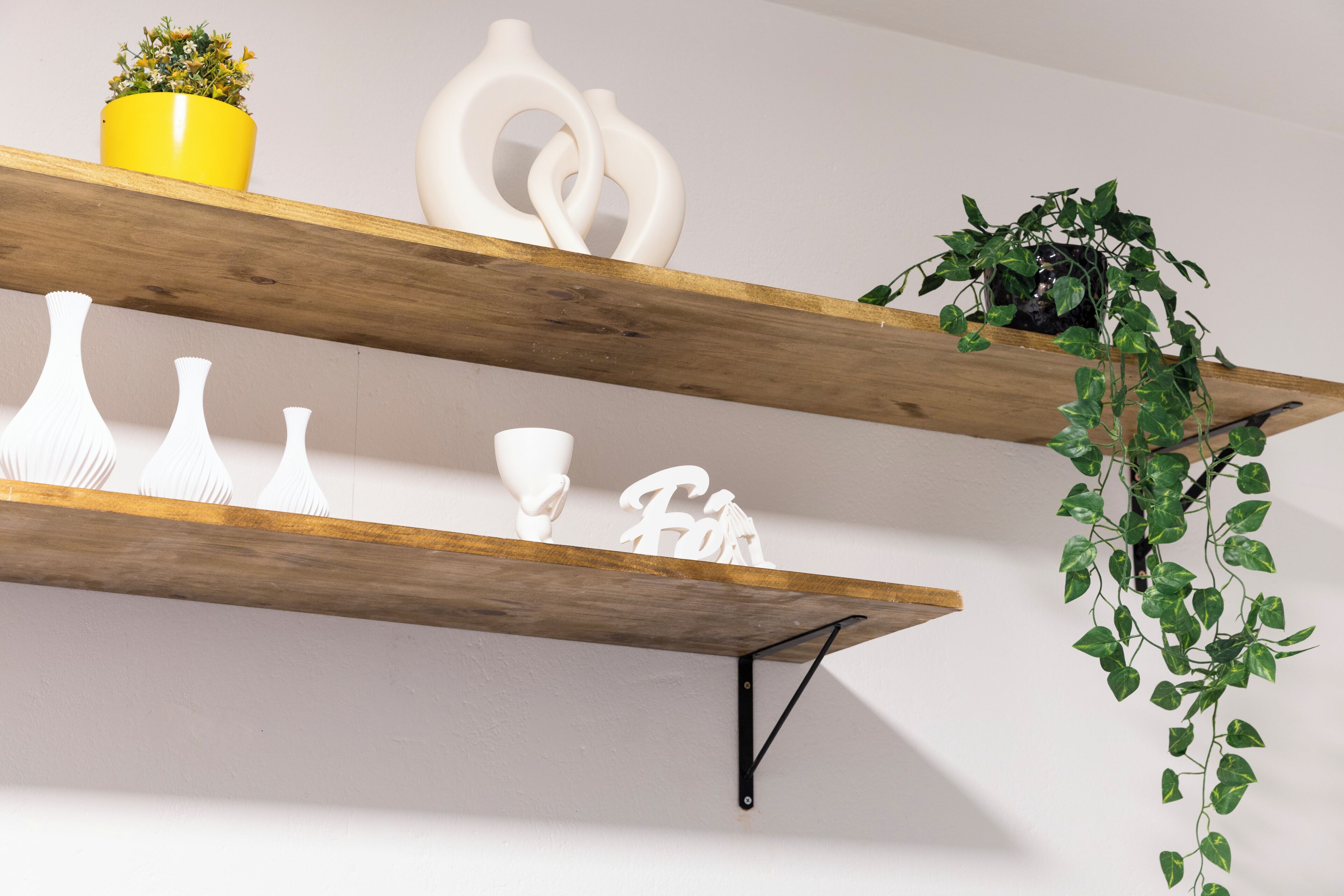 Twee houten planken met decoratieve witte voorwerpen en een potplant.