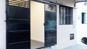 Ένα σύγχρονο κτίριο με μια μαύρη συρόμενη πόρτα, ένα μ ικρό παράθυρο με κάγκελα και ο αριθμός «24» ζωγραφισμένος στον τοίχο.