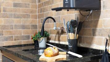 A kitchen with a granite countertop, a sink, a potted plant, and a knife on a cutting board.