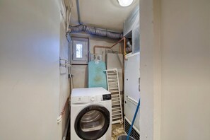 A compact laundry room with a front-loading washing machine, a drying rack, and a small window. - Lou Dava Chic Apt Near Centre Chamonix, Chamonix, France (Chamonix)