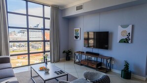Ein modernes Wohnzimmer mit großem Fenster, Flachbildfernseher und Essbereich.