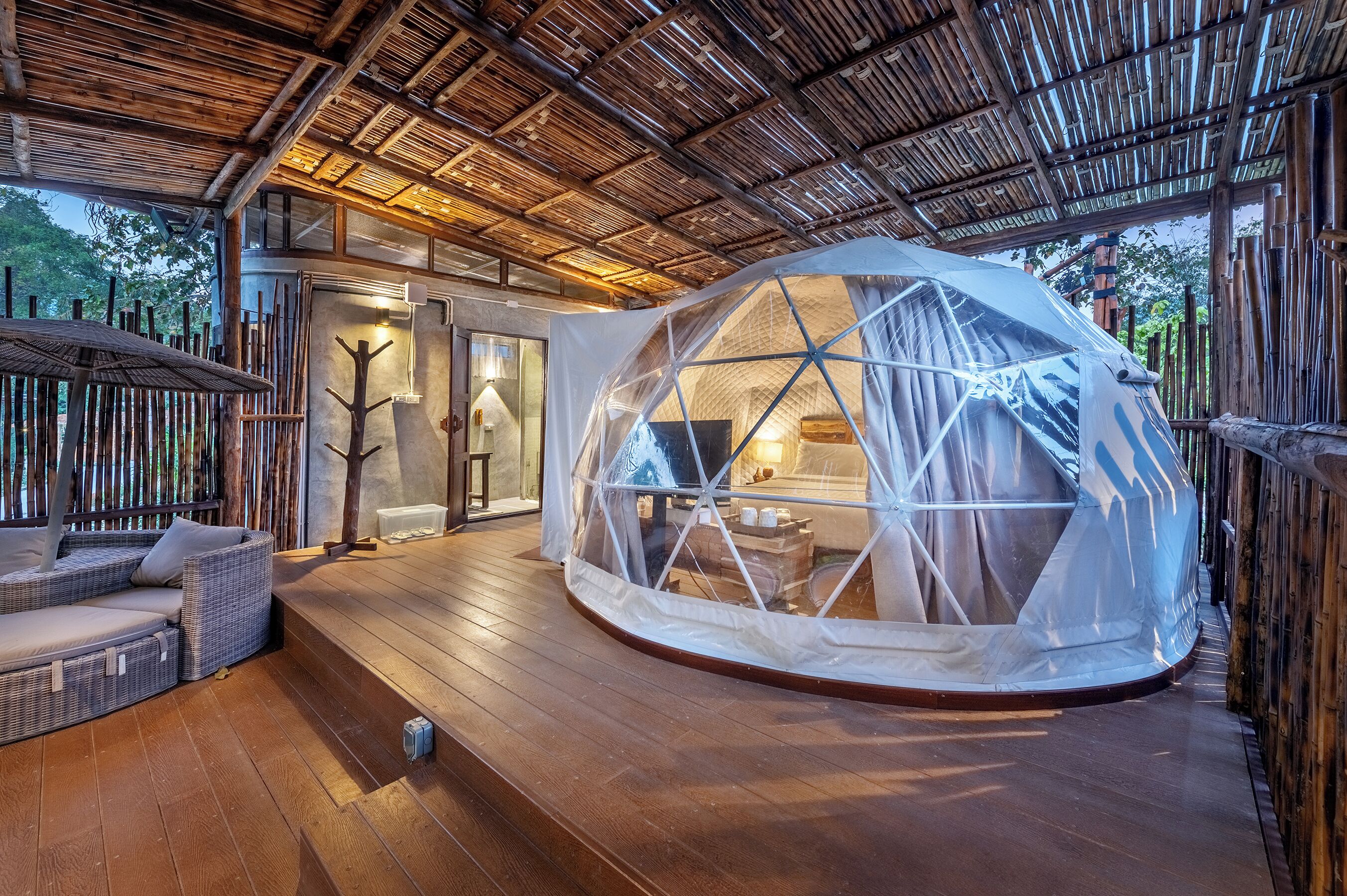 A geodesic dome structure with a wooden deck and wicker furniture.