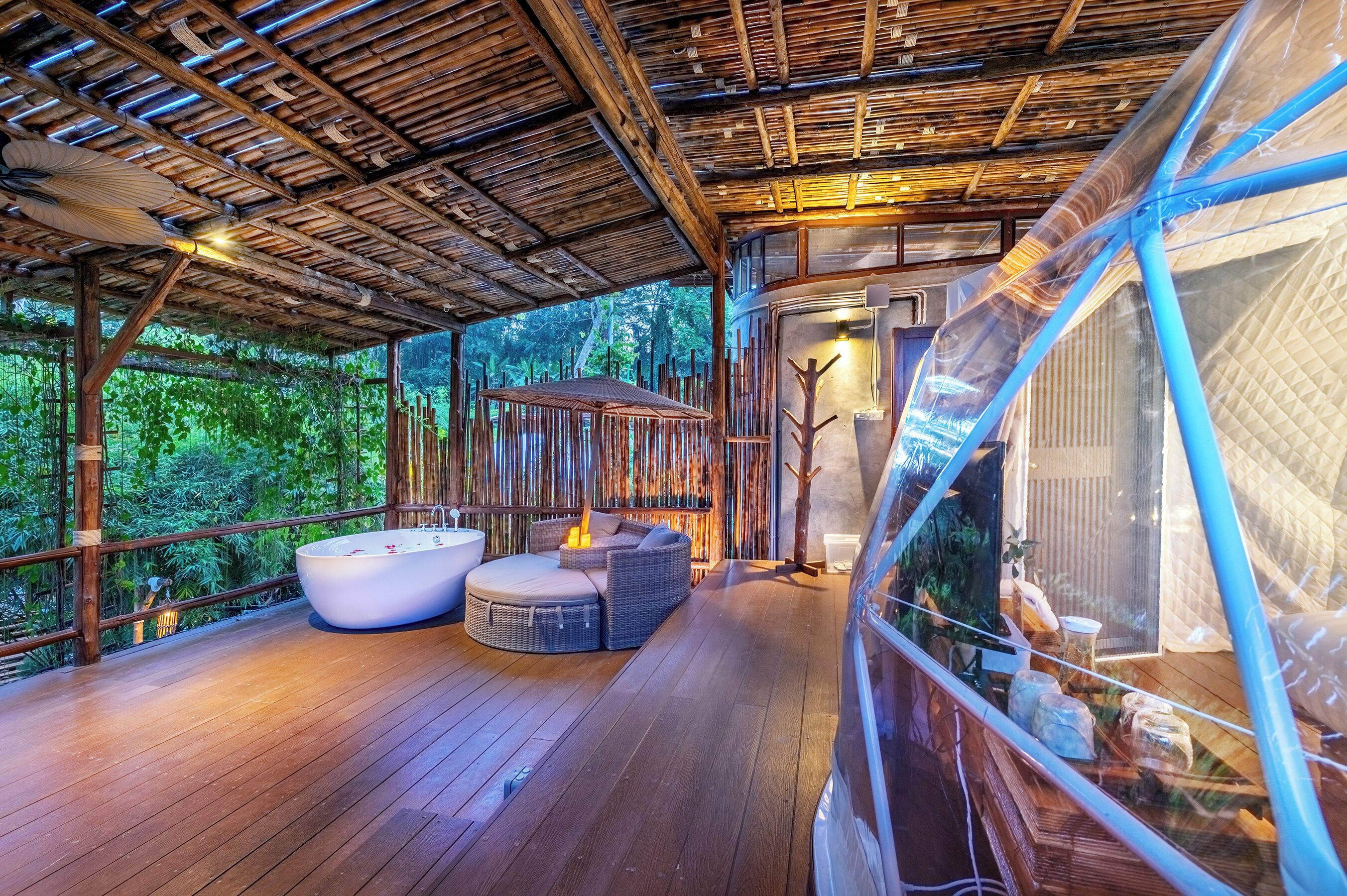 A wooden deck with a hot tub and seating, surrounded by bamboo walls and glass enclosures.