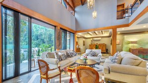 Amplia sala de estar con ventanas grandes, un techo alto y vistas al exterior.