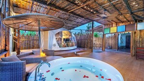 Un área de spa con jacuzzi, mobiliario de mimbre y estructura de bambú.