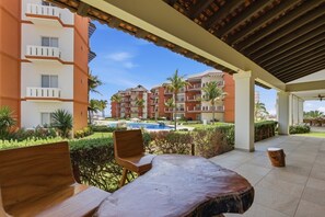 Un espacio exterior cubierto con piscina, sillas de descanso y vistas a edificios de varios pisos.