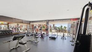 Une salle de sport équipée de tapis de course, d’appareils de musculation et d’un rameur.