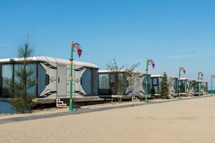 Una hilera de vehículos recreativos estacionados junto a un cuerpo de agua, bajo un cielo despejado.