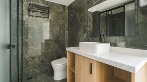 Ein modernes Badezimmer mit Marmorwand, einem weißen Waschbecken und einem Holzkabinent.