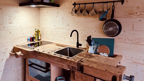A compact kitchen with a wooden workbench, a sink, and a hanging pot rack. - Beautiful, gently renovated apartment in the beautiful Bernese Oberland. (Frutigen)