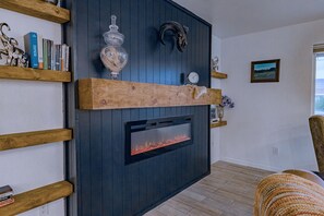 A modern living room with a built-in fireplace, wooden shelves, and a mounted clock. - Stardust Borrego — Movie Lounge + Bar • Fire Pit • AC • Pet-Friendly Retreat (Borrego Springs)