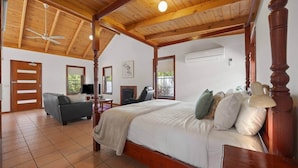 Een slaapkamer met een hemelbed, een bank, een televisie en een open haard.